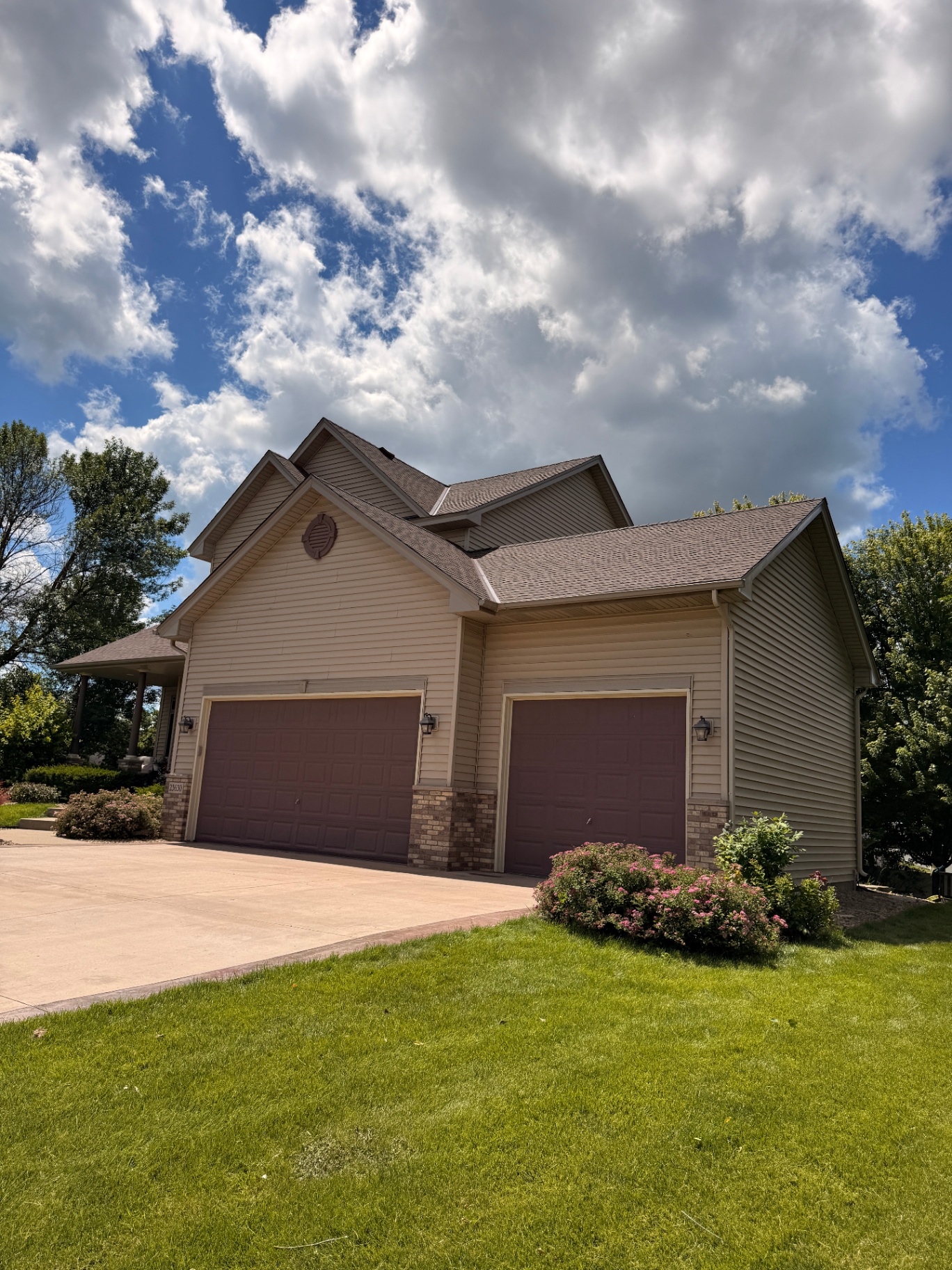 Side elevation of a completed storm-damage roof replacement in Rogers, MN with crisp ridge line and color-matched gutters