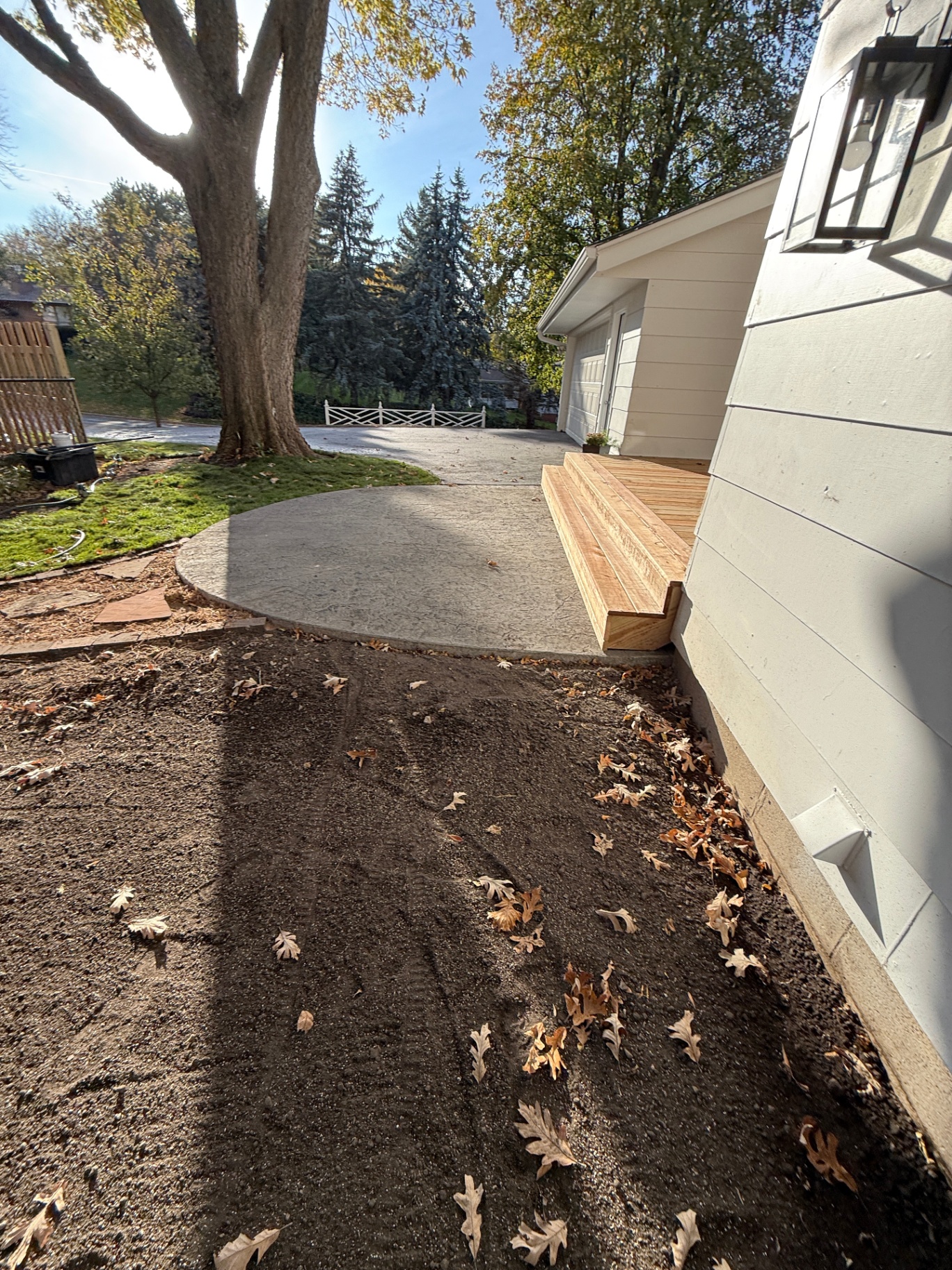 Curved edge of the texture-mat stamped concrete patio meeting the new wood deck steps at the Burnsville, MN home
