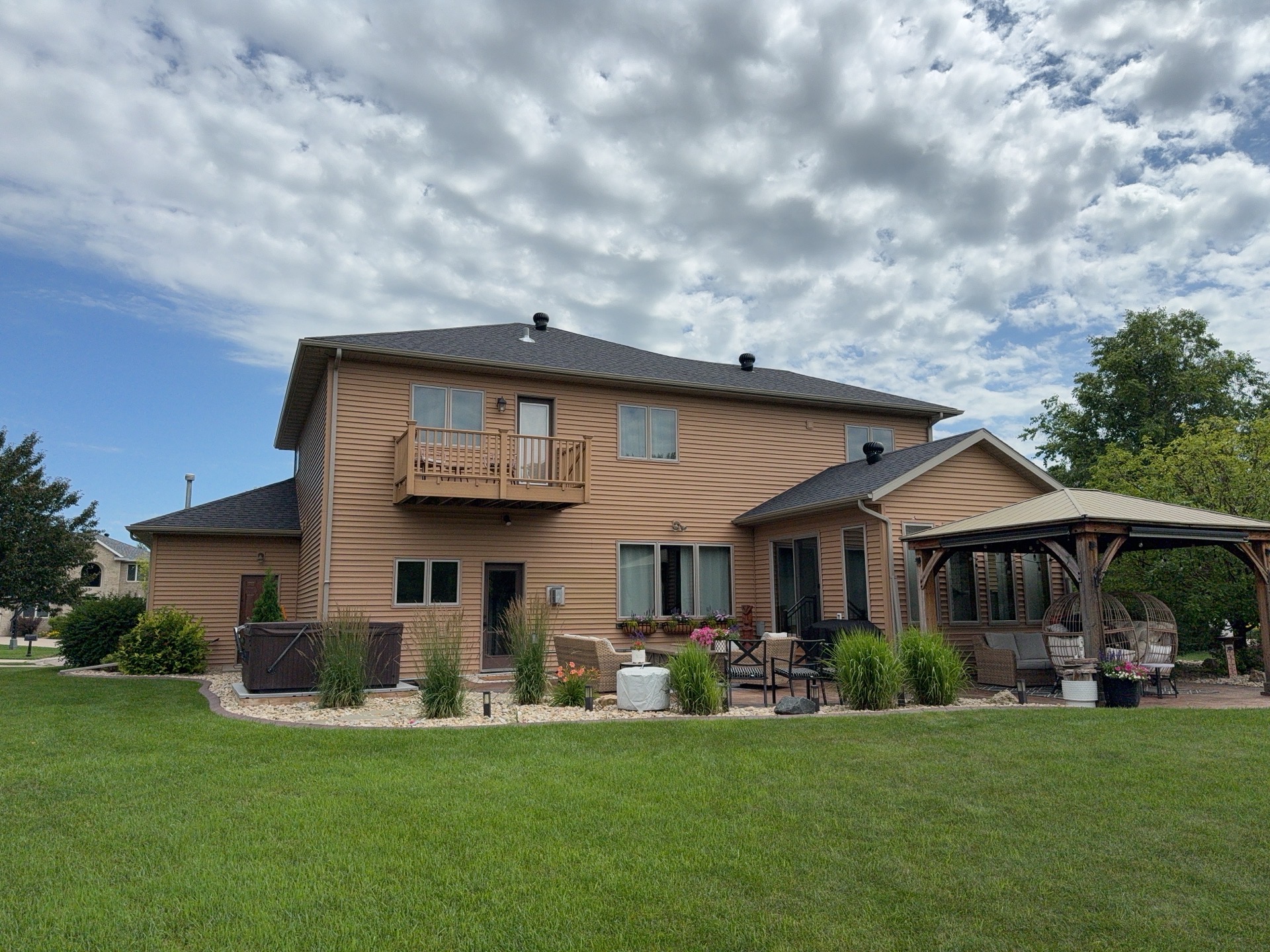 Rear yard of a Moorhead, MN home with existing brown lap vinyl siding and a gazebo before a full siding replacement