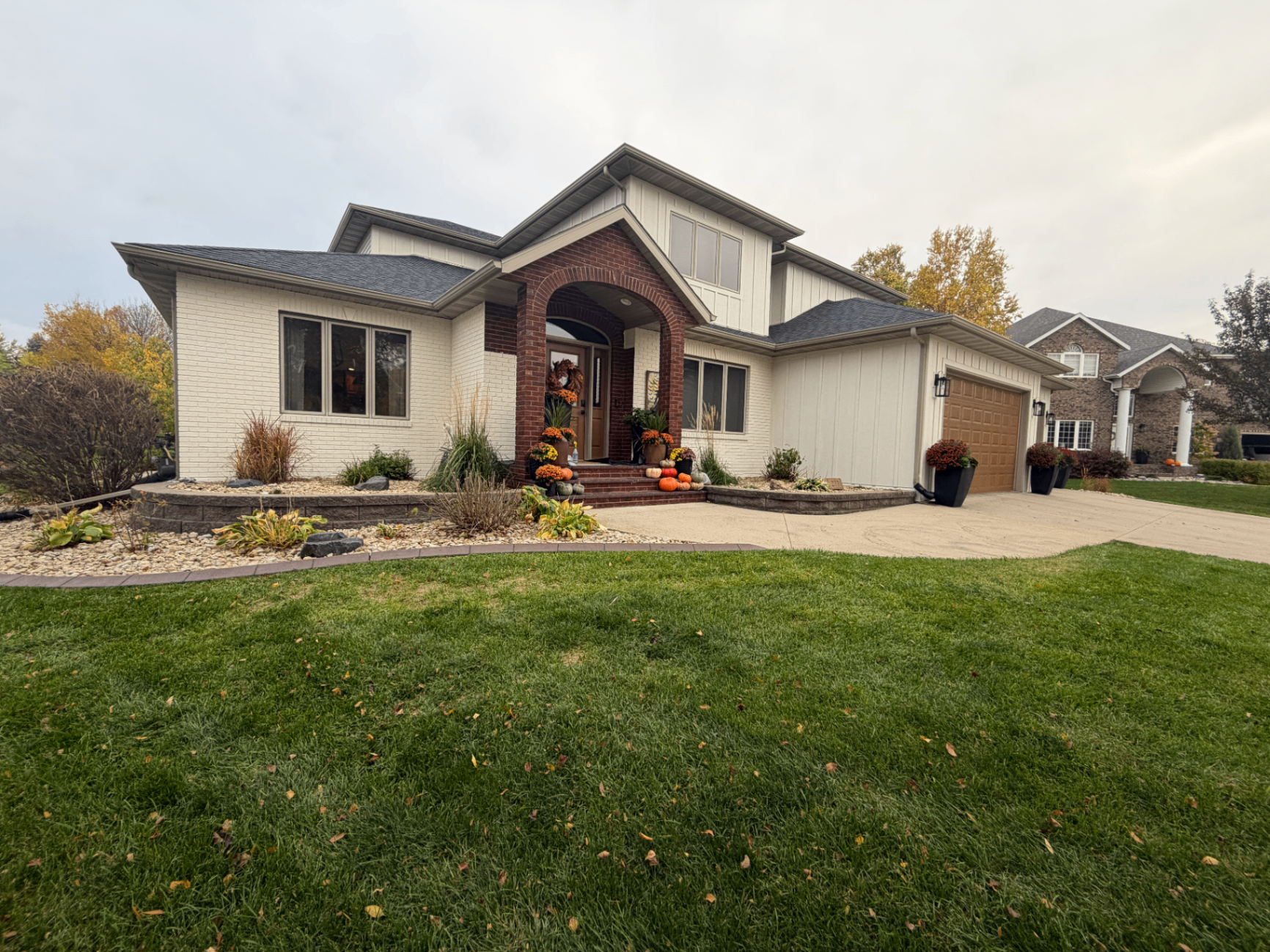 Angled view of a Moorhead, MN home's brick front entry porch and garage after new cream board & batten siding was installed