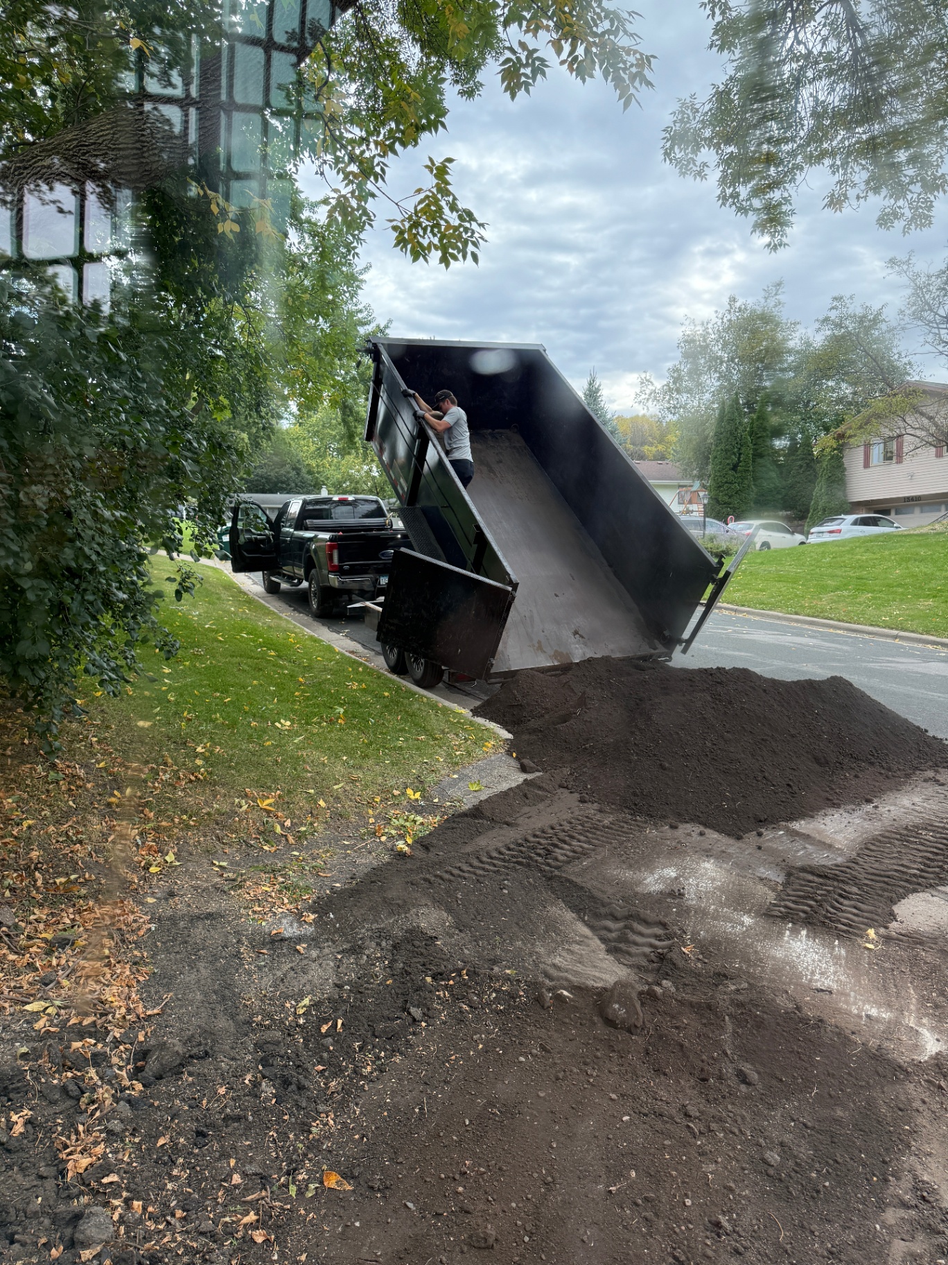 Dump trailer offloading a load of screened black dirt at the curb of the Knob Hill home in Burnsville, MN