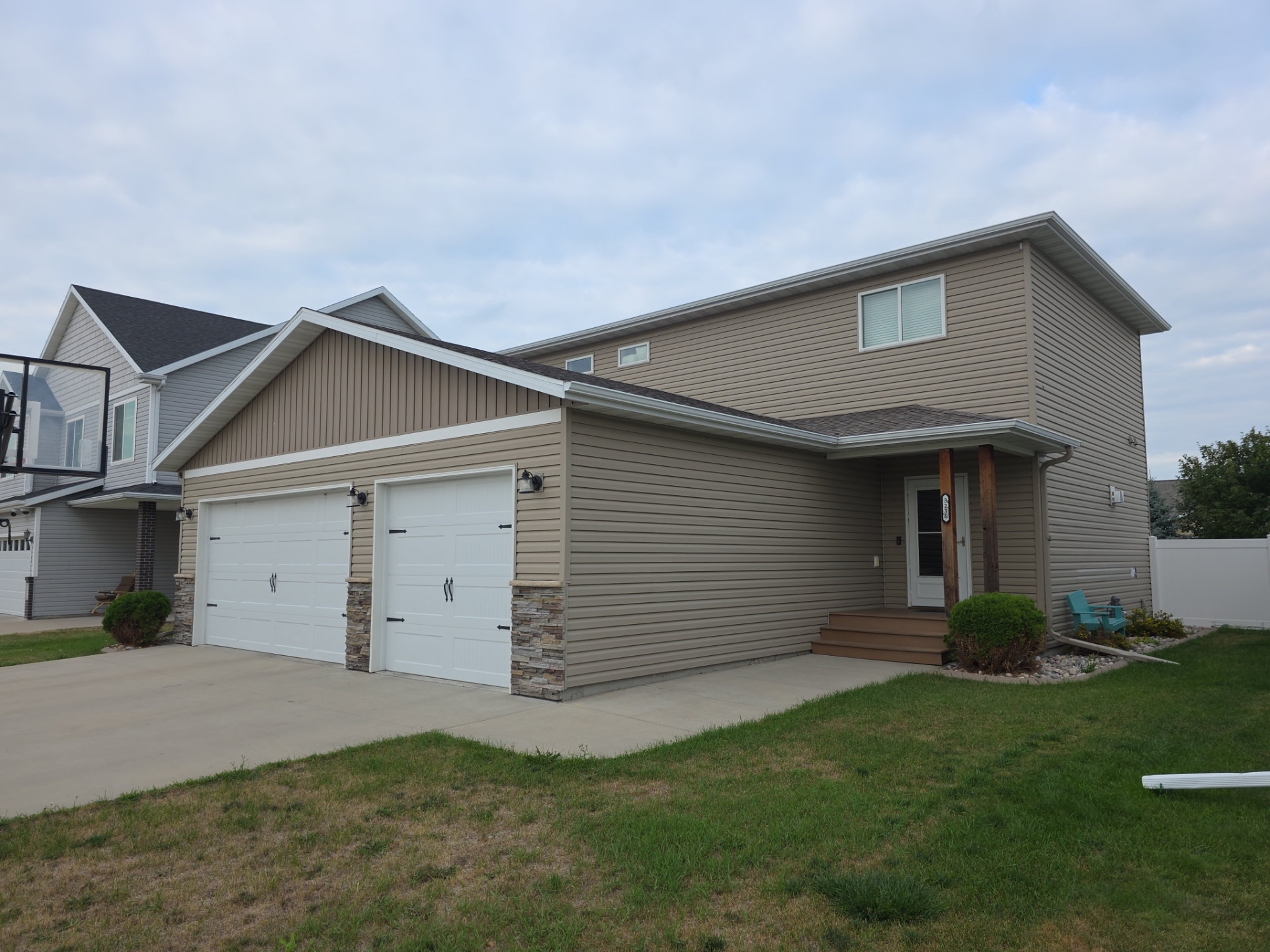 Before photo of a Moorhead, MN two-story home with discontinued Clay-colored vinyl siding and a hail-damaged shingle roof, photographed before an insurance-covered roof and siding replacement