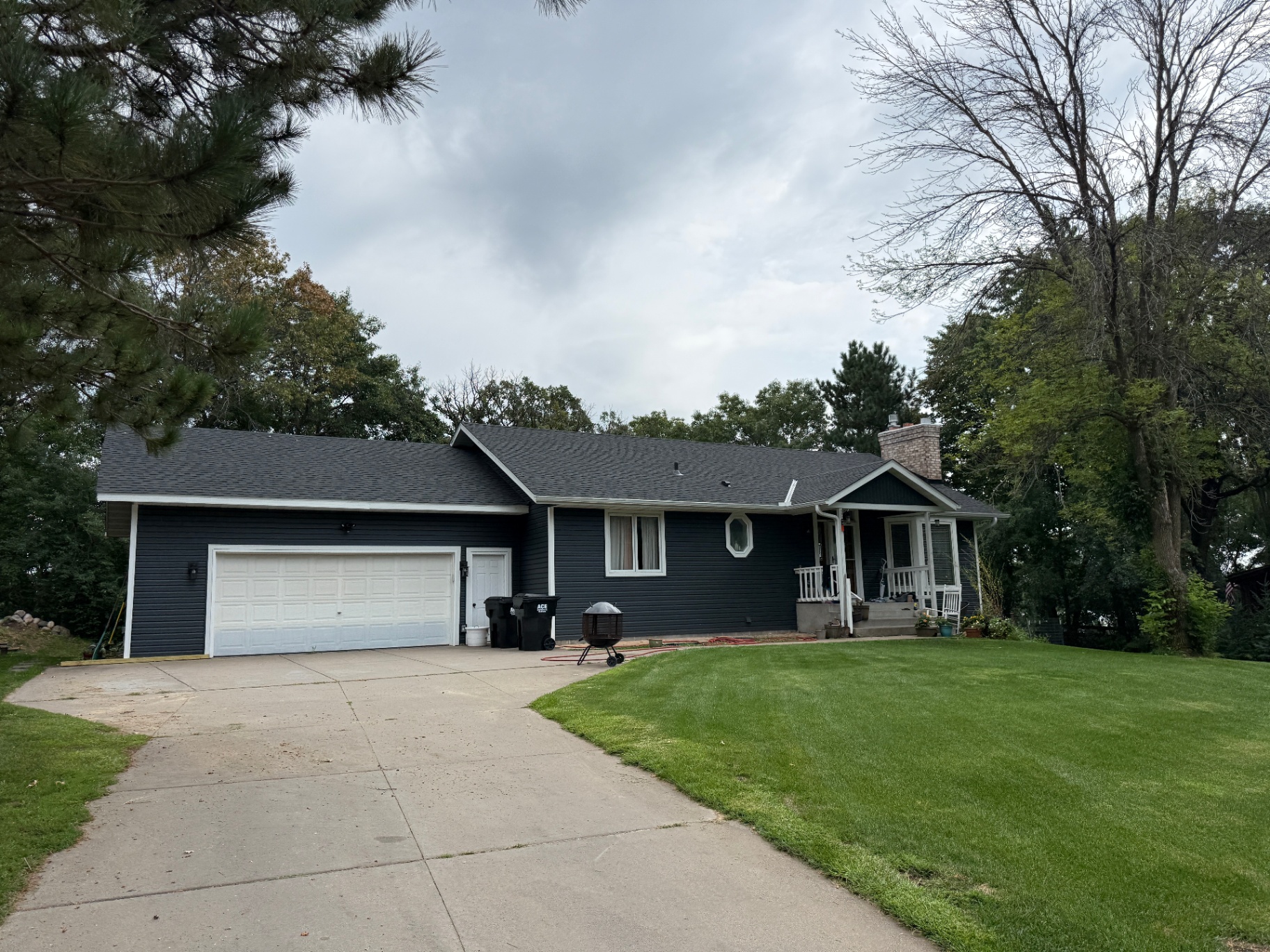 Elk River, MN home after the 2026 roofing and siding replacement, showing the new GAF Timberline HDZ Charcoal roof, Royal Brunswick siding, and white corner and window accents