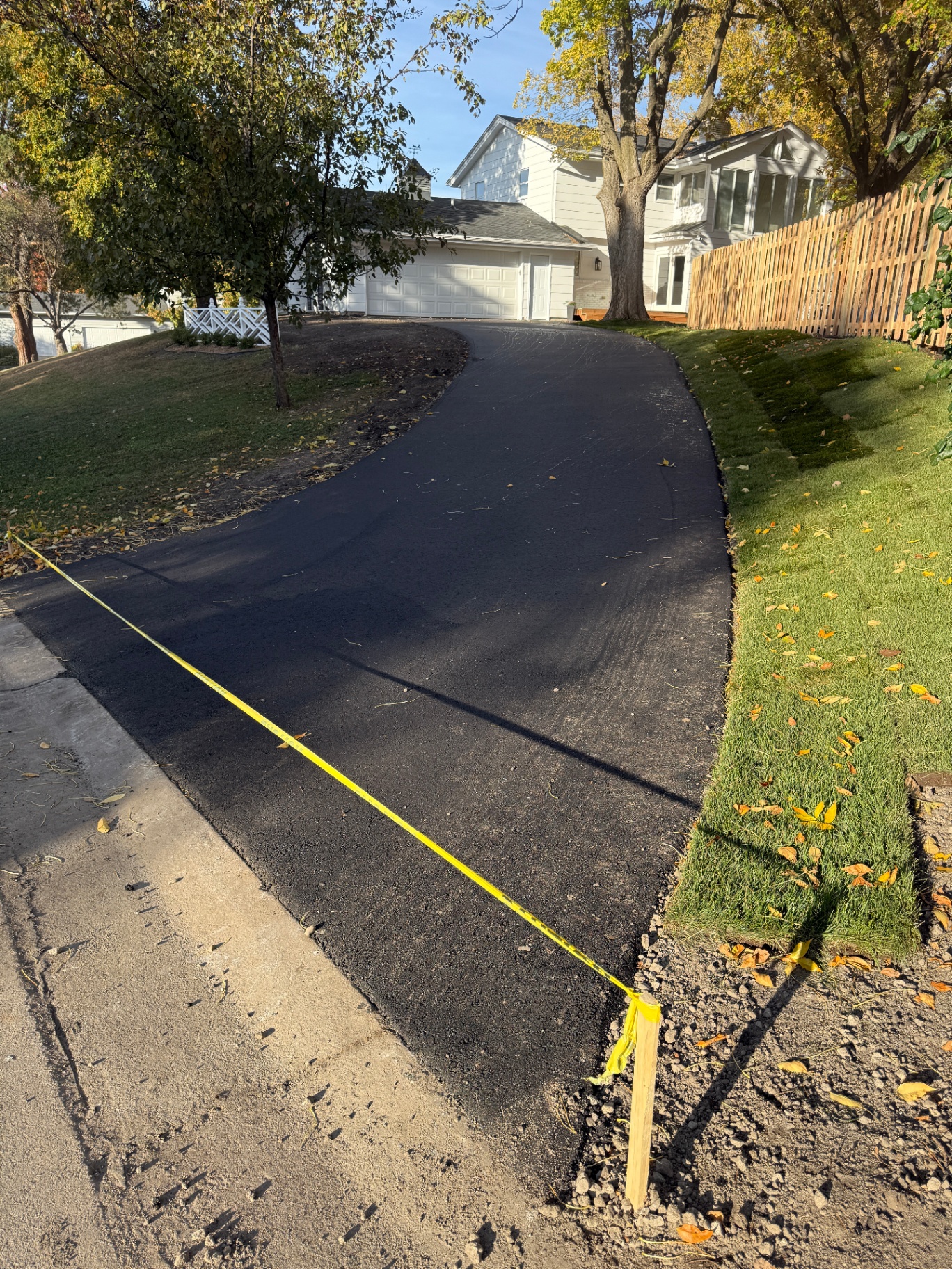 New asphalt backyard driveway with clean edges and fresh sod alongside in Burnsville, MN