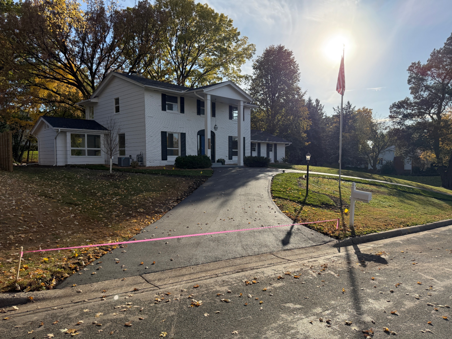 Original aged asphalt driveway before replacement, pink layout paint marking the new apron