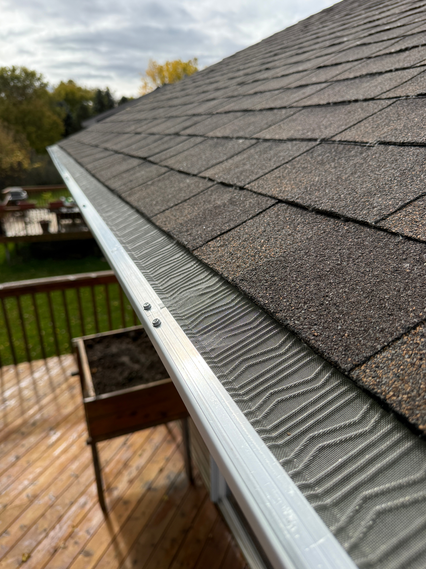 LeafBlaster Pro stainless steel micro-mesh leaf guard installed along the gutter of an Andover, Minnesota home, tucked under the first course of shingles and fastened to the gutter front lip